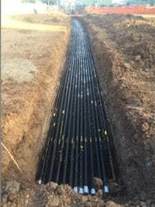 Black electrical conduit installed in trench, red cedar